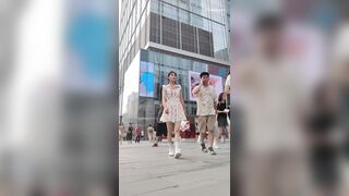 白い花柄のドレスを着た若い女性がボーイフレンドと一緒に買い物に来ています。彼女はフィットした黒のトップスを着ています ipcam 1